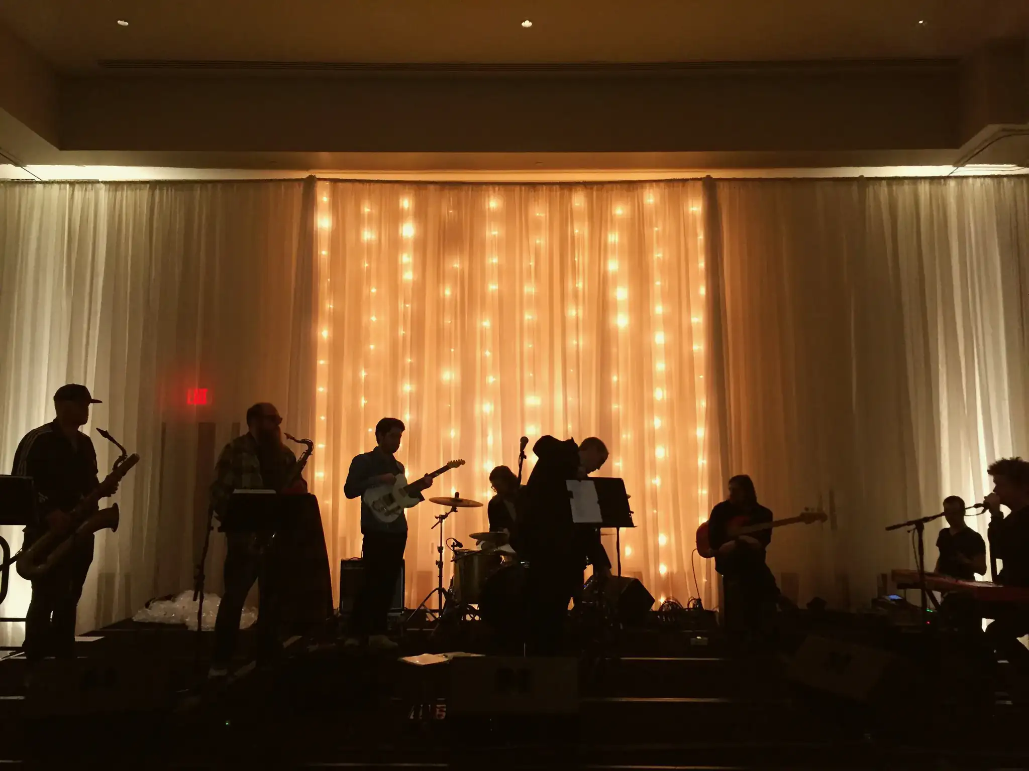 Live band performing with warm orange backdrop lighting