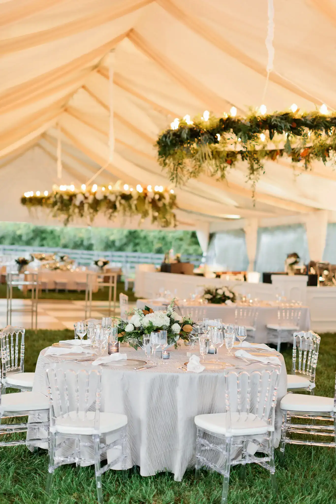 Wedding tent reception with floral garlands and string lights
