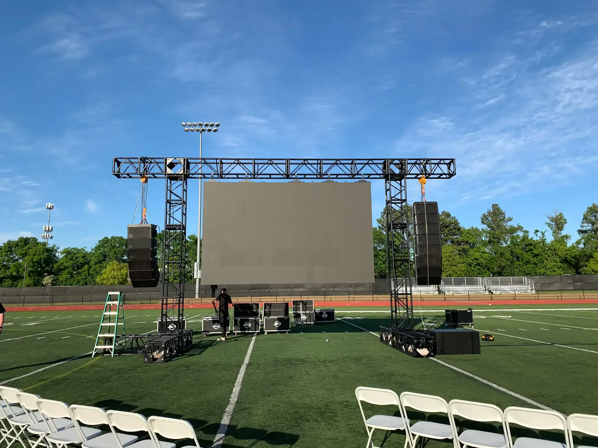 Outdoor festival field with large projection screen at night
