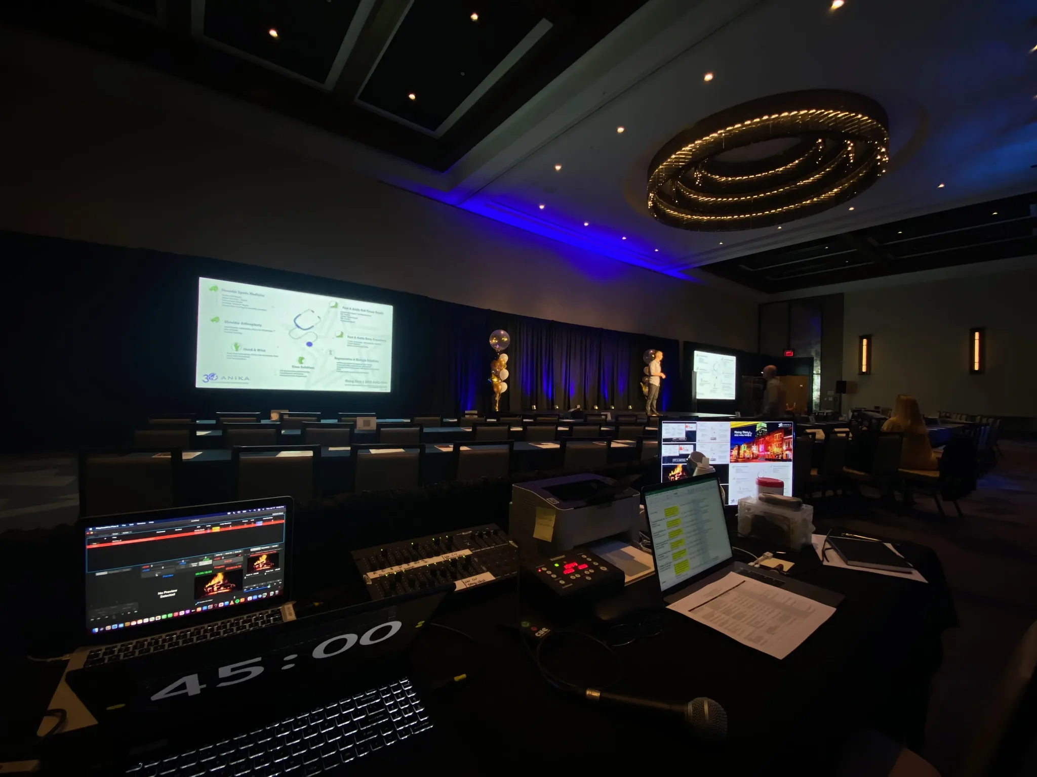 Corporate conference stage with blue uplighting and projection